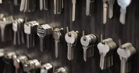Rows of differently shaped keys for copying or duplicating hanging on hooks against a black background.